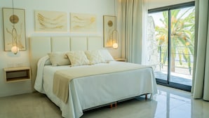 A modern bedroom with a large bed, bedside tables, and artwork on the walls. - Palmas de la Laguna by Posada Suiza (San Miguel del Monte)