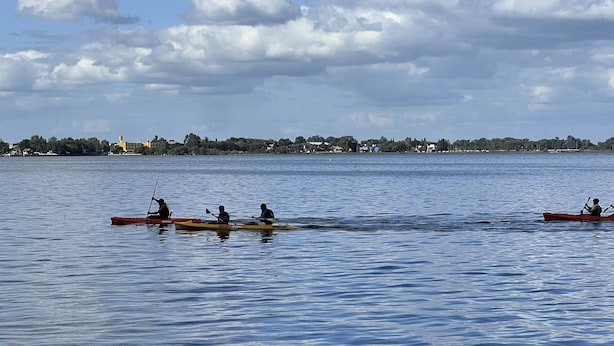 A calm lake with kayaks and a distant shoreline with buildings. - Palmas de la Laguna by Posada Suiza (San Miguel del Monte)