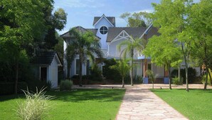A house with a stone pathway leading to the entrance, surrounded by well-maintained lawns and trees. - Posada Suiza by Prima Collection (San Miguel del Monte)