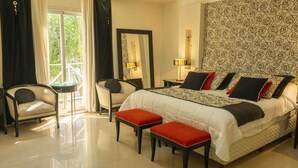 A bedroom with a large bed, two bedside tables, a chair, and a bench. - Posada Suiza by Prima Collection (San Miguel del Monte)