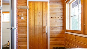 Een kamer met houten lambrisering, een deur, een bank en een raam.