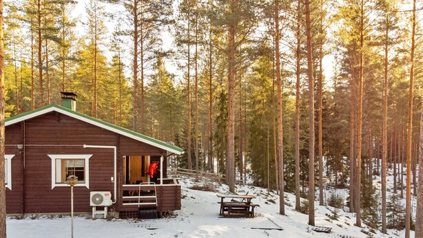 Een chalet met veranda, een bank en een ladder.