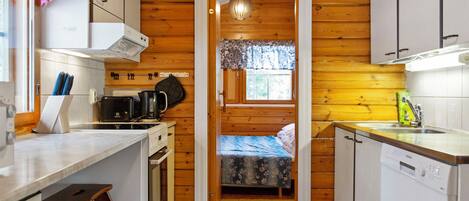 Una cocina compacta con paredes de madera, una zona de comedor y un dormitorio pequeño con ventana.