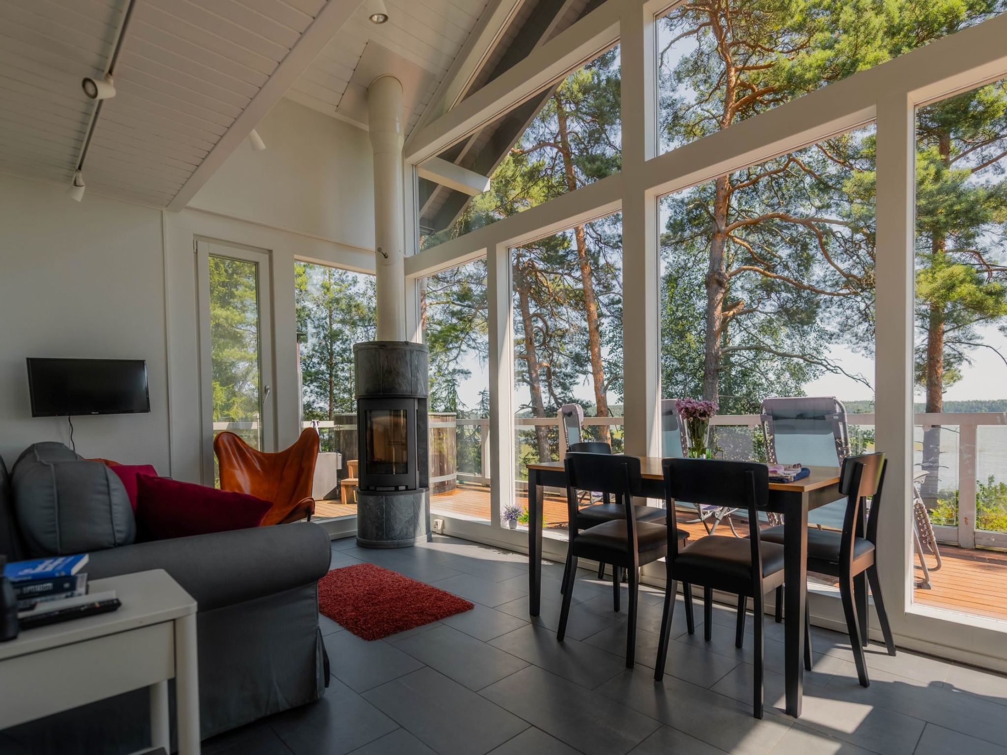 A modern living room with a fireplace, large windows, and a dining area with outdoor views.