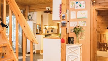 Ein Holzinterieur mit Küchenzeile, einem weißen Kühlschrank und einer Wand mit Kinderzeichnungen.