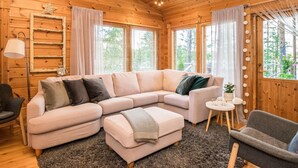 L’intérieur d’un chalet en bois chaleureux et accueillant, avec un canapé d’angle, une petite table ronde et un fauteuil.