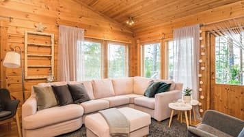 Ein gemütliches Holzinterieur mit einer Eckcouch, einem kleinen runden Tisch und einem Sessel.