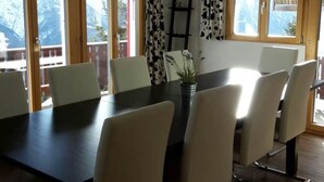 Un coin repas avec une longue table, six chaises et une plante en pot.
