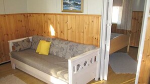Een kamer met houten lambrisering, een bank, een bed en een klein vloerkleed.