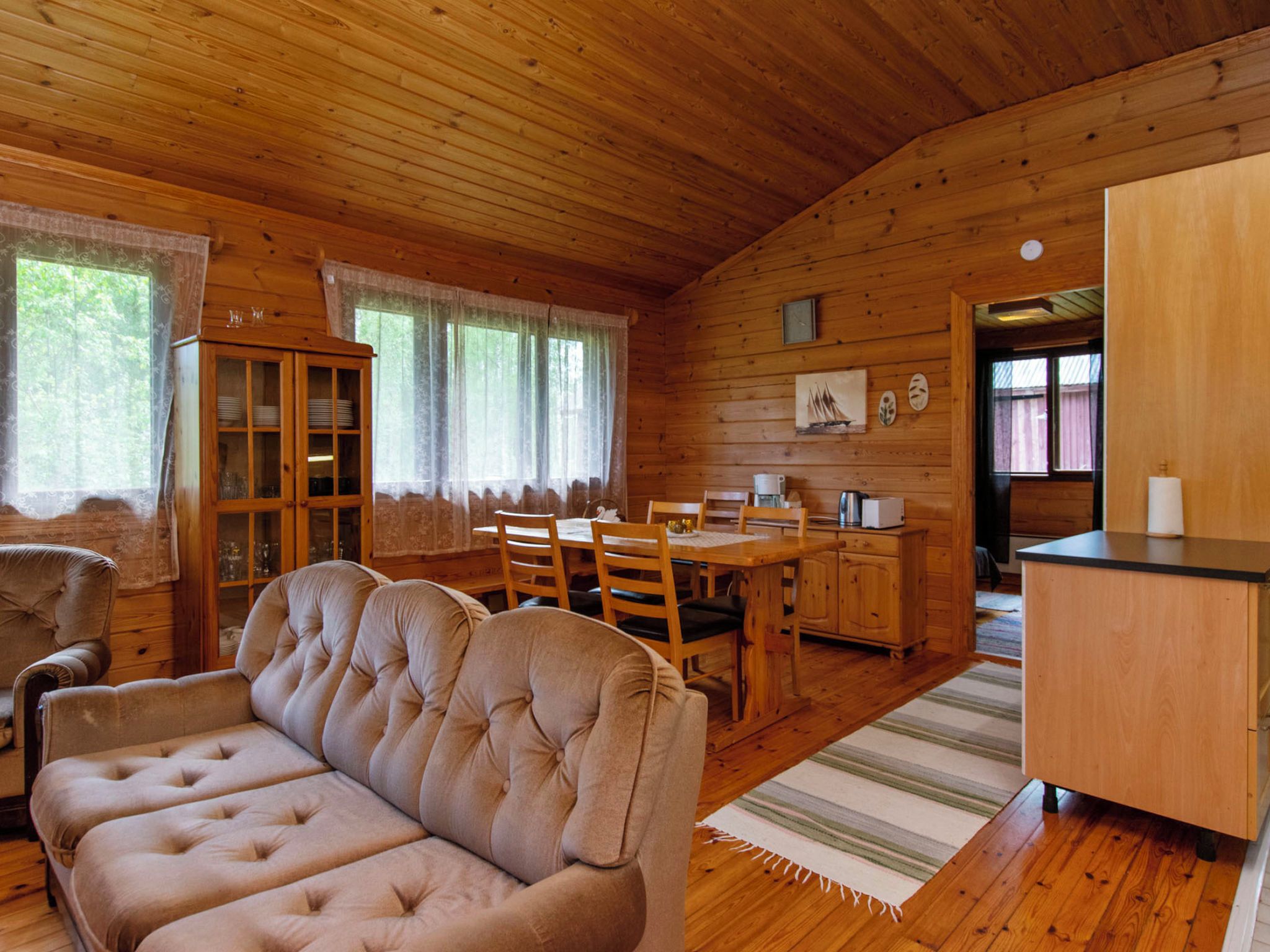 Un intérieur de chalet chaleureux et accueillant, avec un coin repas, un canapé et une cuisine.