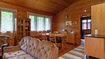 Un intérieur de chalet chaleureux et accueillant, avec un coin repas, un canapé et une cuisine.