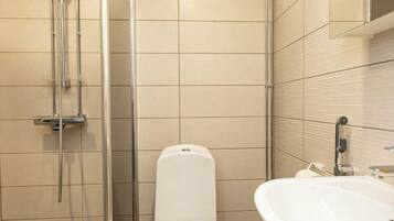 A bathroom with a toilet, a shower enclosure, and a sink.