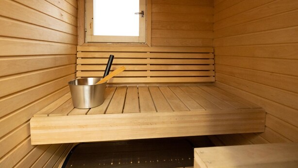 A sauna room with wooden walls, a window, a metal basin with a wooden ladle, and a bench. - Koivukuja, katinkullantie by Interhome (Sotkamo)