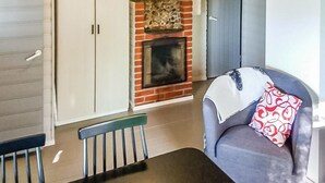 A living room with a fireplace, a dining table, and a sofa. - Kuusela by Interhome (Kaavi)