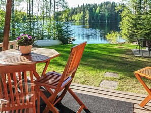 A wooden deck with a table and chairs overlooking a lake surrounded by trees. - Kuusela by Interhome (Kaavi)