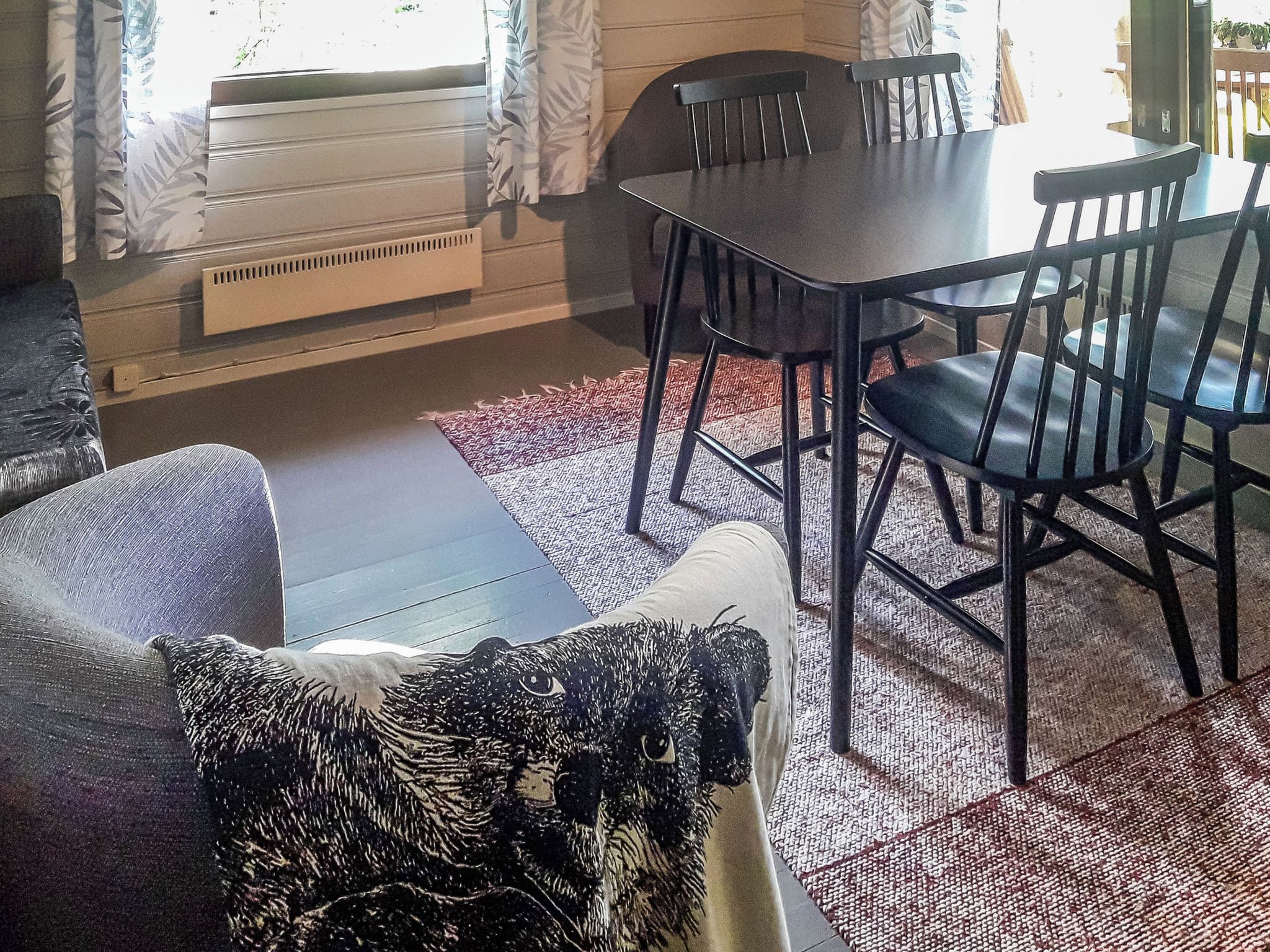 Ein Essbereich mit Tisch und Stühlen, einer Couch und einem gemusterten Teppich.