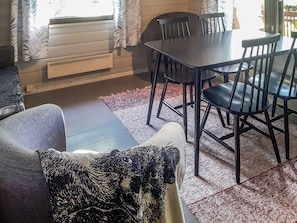 A dining area with a table and chairs, a sofa, and a patterned rug. - Kuusela by Interhome (Kaavi)
