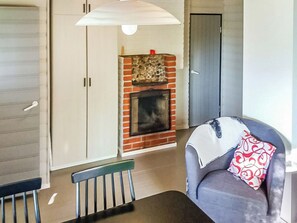 Una sala de estar con chimenea, un sofá con cojín estampado y una mesa de comedor con sillas.
