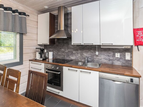 A modern kitchen with white cabinets, a stainless steel range hood, a built-in oven, and a dishwasher.