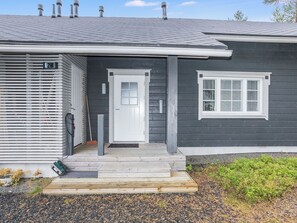 A modern house with a grey exterior, a white front door, and a small window with shutters.