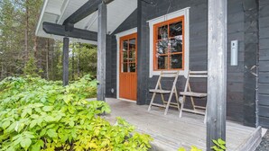 A wooden cabin with a porch, a window with an orange frame, and a ladder leaning against the wall. - Rukanloisto b by Interhome (Kuusamo)