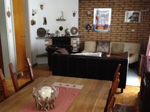 Una sala de estar con chimenea, un sofá y una mesa de comedor con sillas.