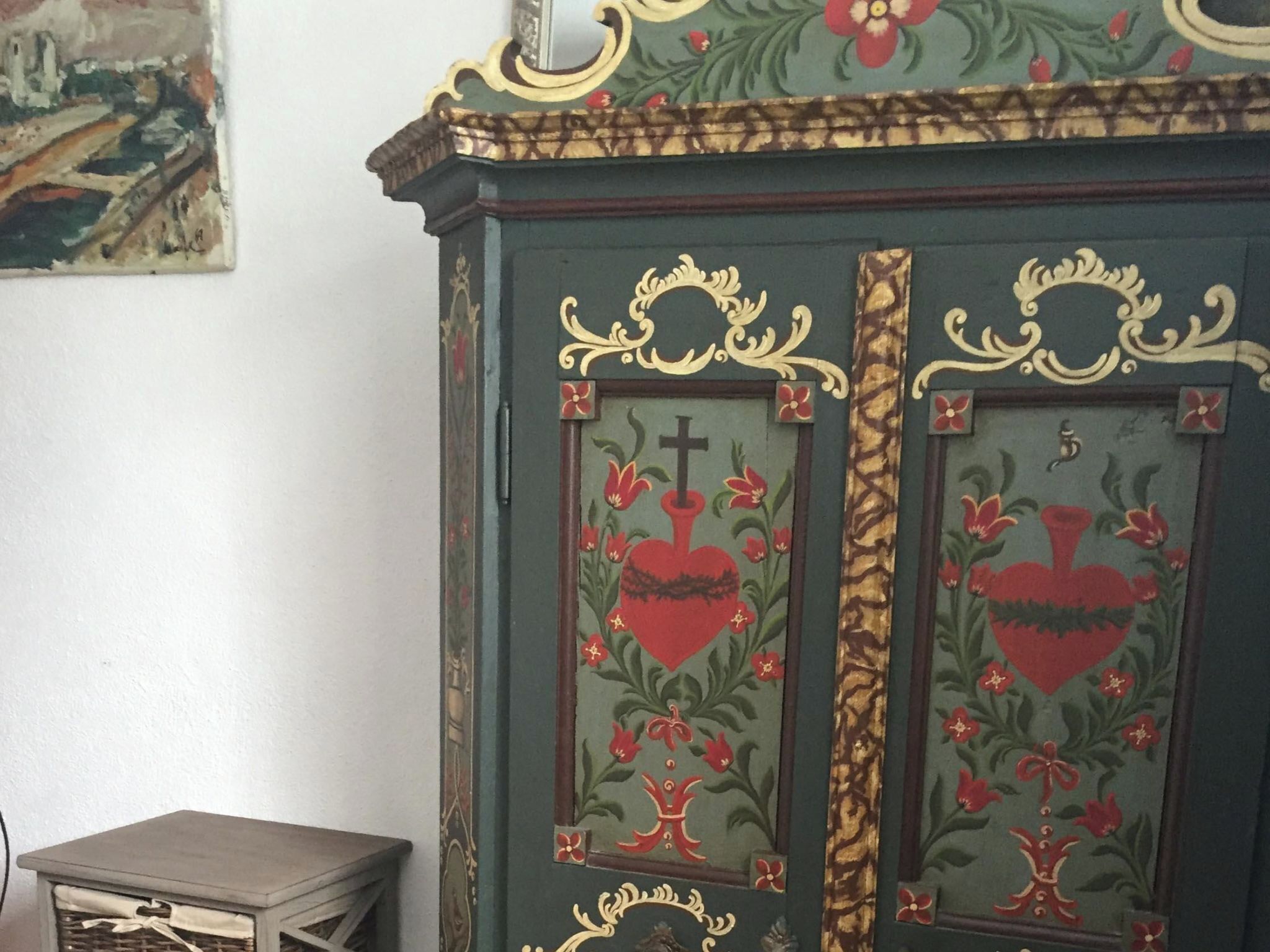 Un mueble verde con detalles dorados ornamentales y motivos florales.