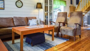Una sala acogedora con una mesa de centro de madera, un sofá marrón y dos sillones de mimbre.