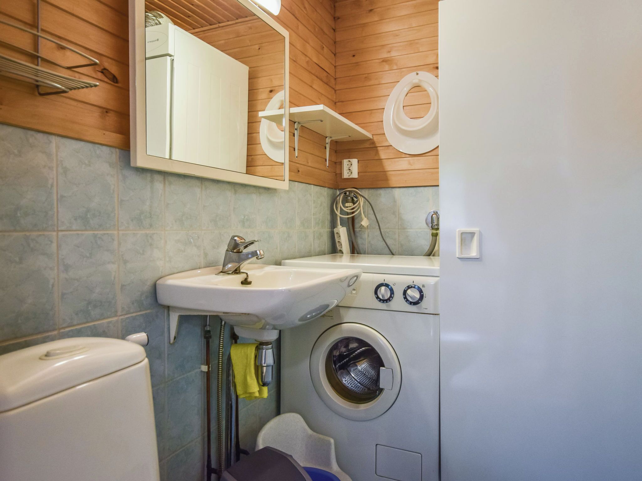 A compact bathroom with a sink, toilet, and washing machine.
