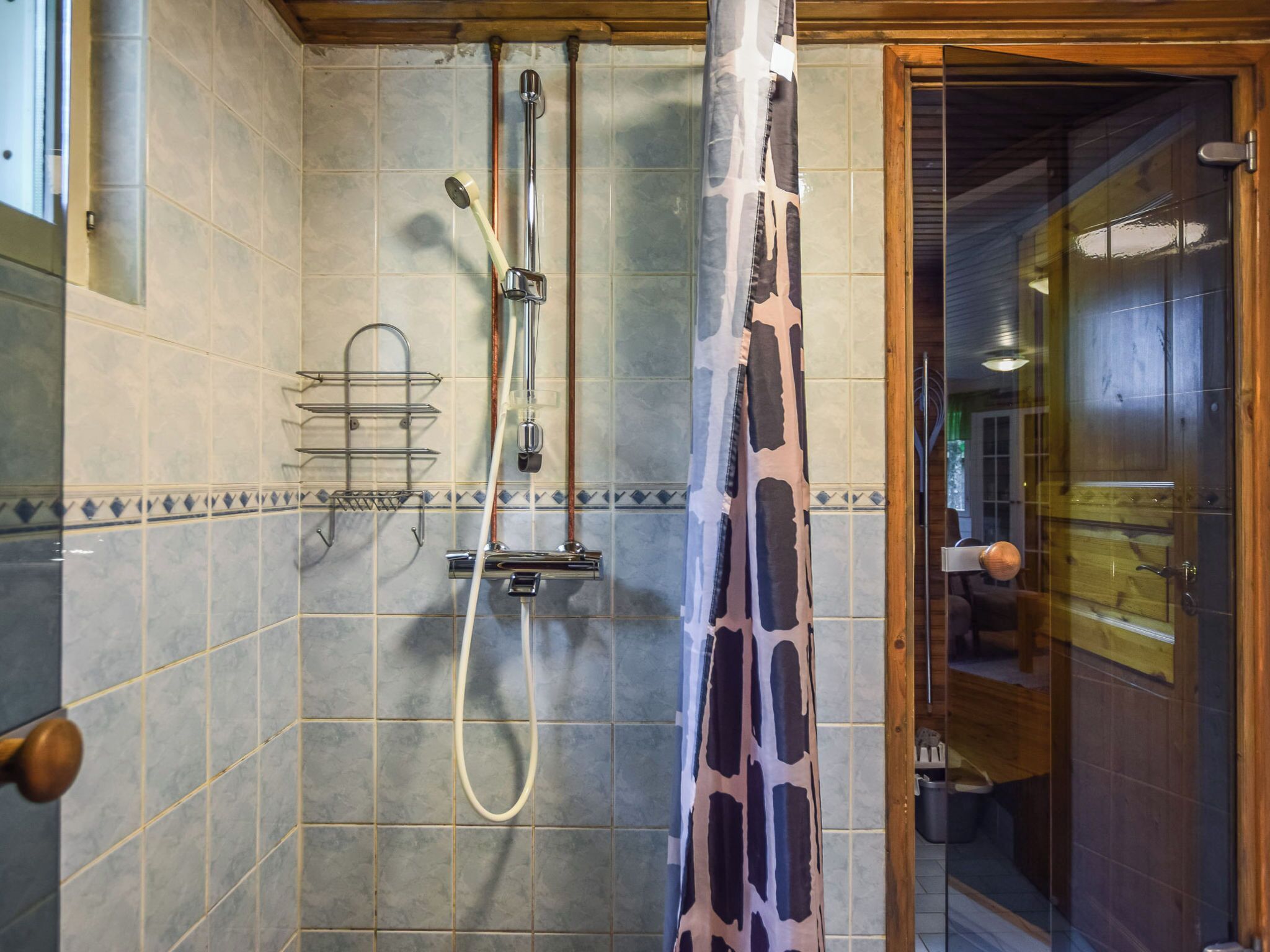 Ein Badezimmer mit Dusche, Handtuchhalter und Holztür.
