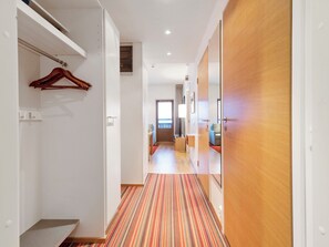 Un pasillo de hotel con alfombra a rayas, puertas de madera y un perchero.