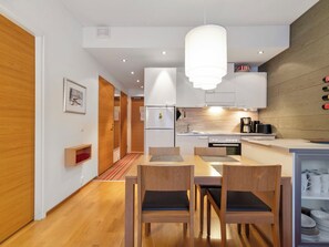 A modern kitchen with a dining area, wooden flooring, and a pendant light.