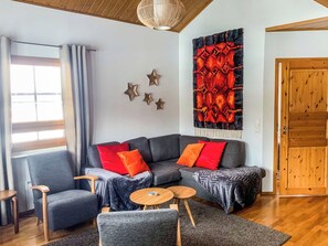 A modern living room with a sectional sofa, two armchairs, a coffee table, and a decorative wall piece. - Alppitähti by Interhome (Nilsiä)