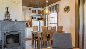 A cozy living room with a fireplace, wooden dining table, and chairs. - Alppitähti by Interhome (Nilsiä)