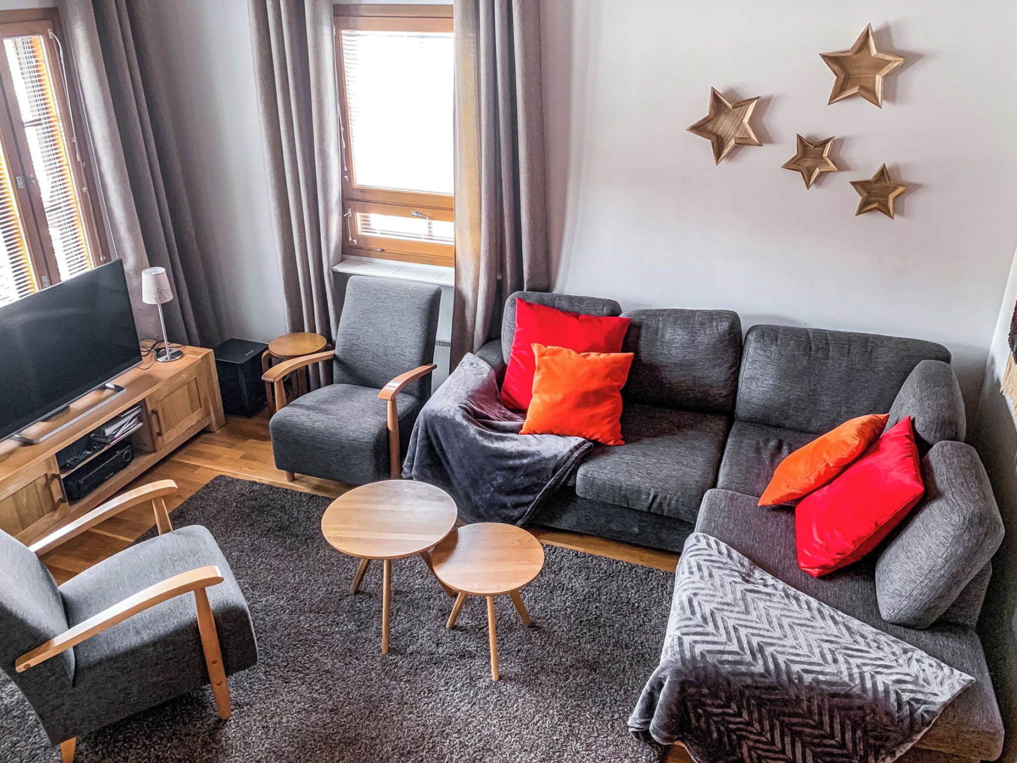 Een moderne woonkamer met een grijze bank, een houten salontafel en een televisie op een houten dressoir.