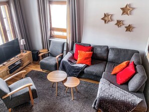 A modern living room with a grey sofa, wooden coffee table, and a TV on a wooden stand. - Alppitähti by Interhome (Nilsiä)
