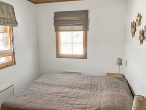 A bedroom with a bed, a window with blinds, a radiator, and a lamp on a bedside table. - Alppitähti by Interhome (Nilsiä)