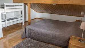 A bedroom with a sloped ceiling, a bed, a white shelving unit, and a lamp. - Alppitähti by Interhome (Nilsiä)