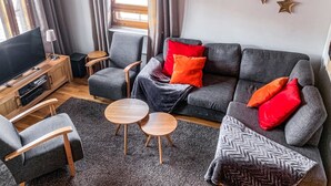 A modern living room with a grey sofa, two armchairs, a TV, and a small wooden table. - Alppitähti by Interhome (Nilsiä)