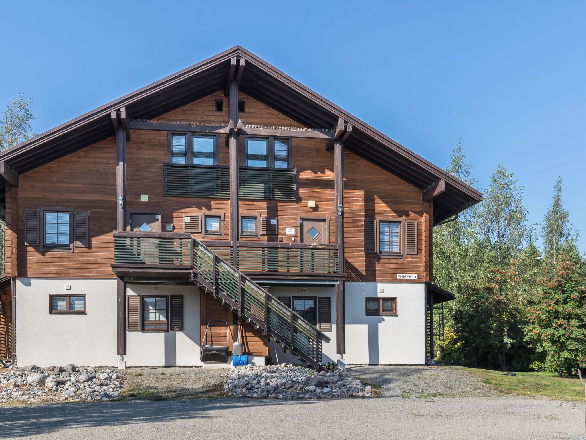 A multi-story wooden building with a balcony and a staircase leading to the entrance.