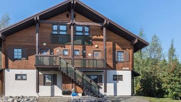 A multi-story wooden building with a balcony and a staircase leading to the entrance.