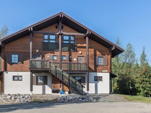 A multi-story wooden building with a balcony and a staircase leading to the entrance. - Alppitähti by Interhome (Nilsiä)