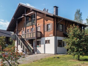 A two-story building with a wooden facade, a balcony, and a staircase leading to the upper floor. - Alppitähti by Interhome (Nilsiä)