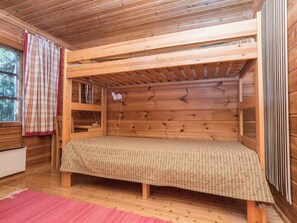 A wooden bunk bed room with a checkered bedspread, a radiator, and a window with curtains. - Uolevintie 39a by Interhome (Kuusamo)