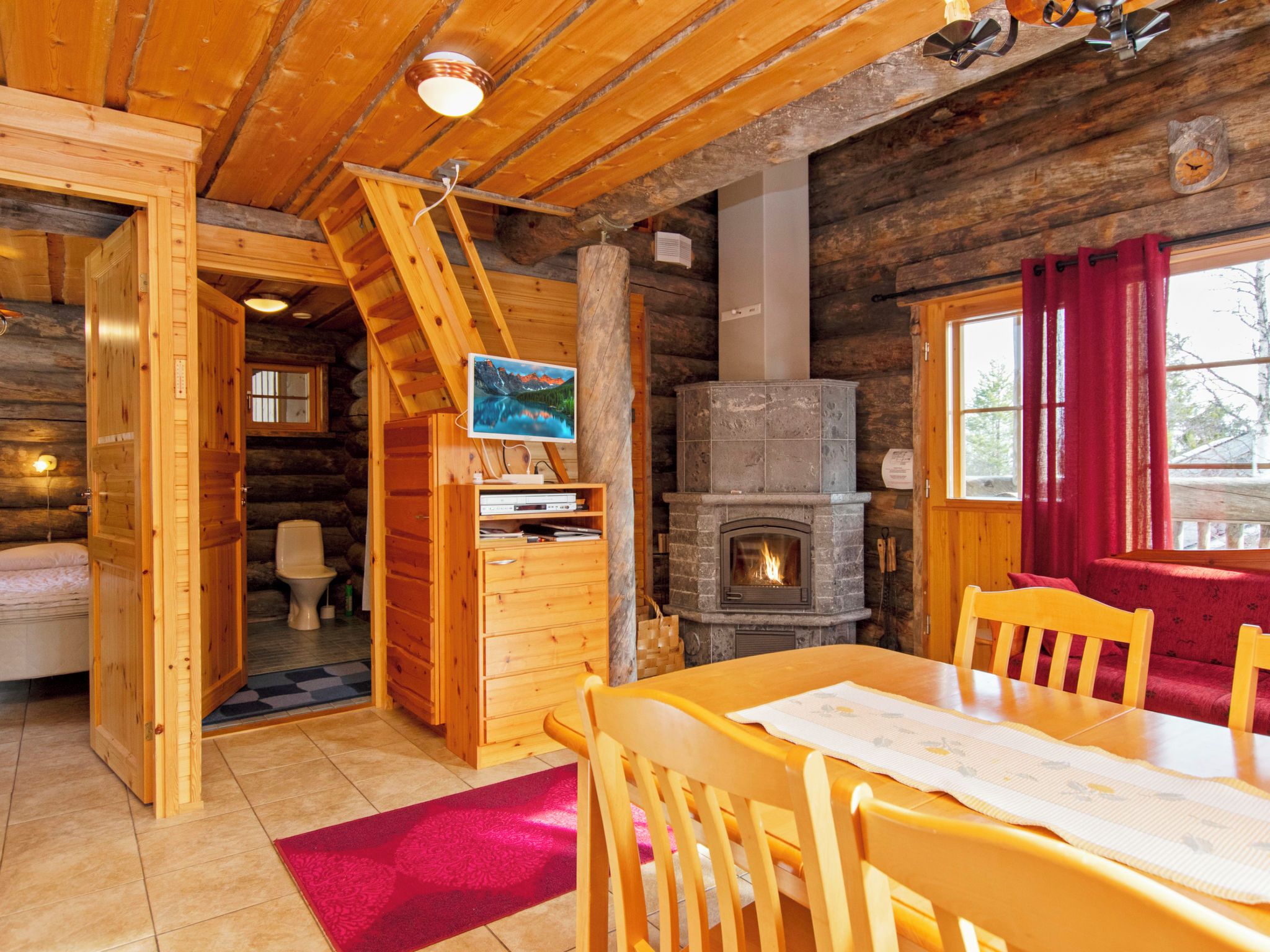 L'interno di una baita di legno con un tavolo da pranzo, sedie, un camino e una scala in legno.