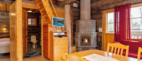 L'interno di una baita di legno con un tavolo da pranzo, sedie, un camino e una scala in legno.