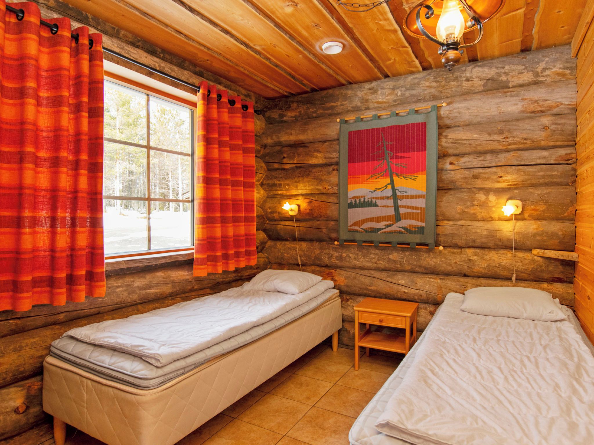 Habitación tipo cabaña con dos camas individuales, una ventana con cortinas, una lámpara de pared y un cuadro.