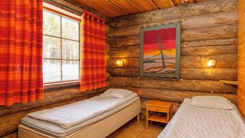 Habitación tipo cabaña con dos camas individuales, una ventana con cortinas, una lámpara de pared y un cuadro.