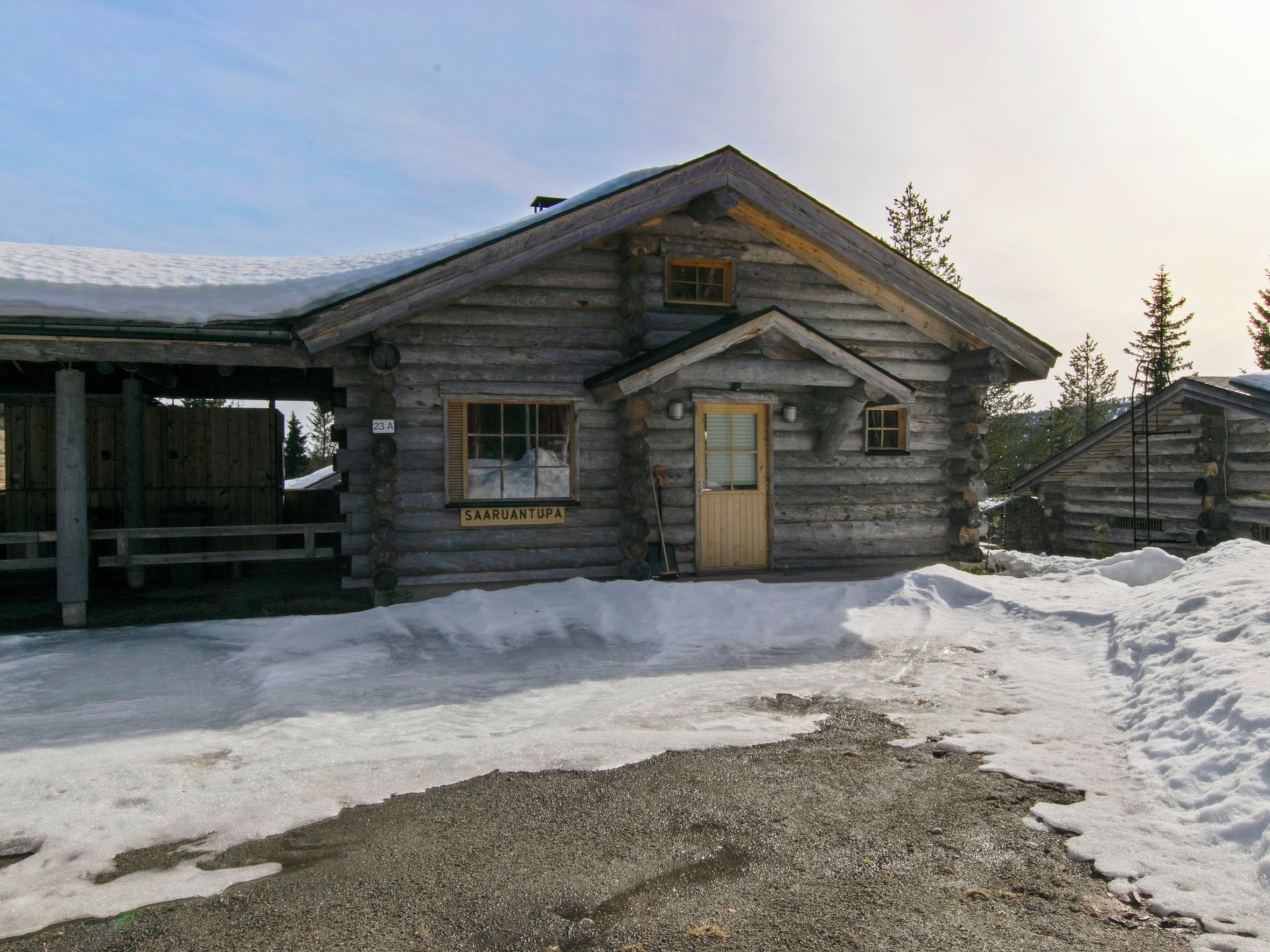 A log cabin with a wooden door and windows, labeled 'SAARUANTUPA,' surrounded by snow.