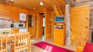 Interior de una cabaña de madera con cocina, comedor y sala de estar.